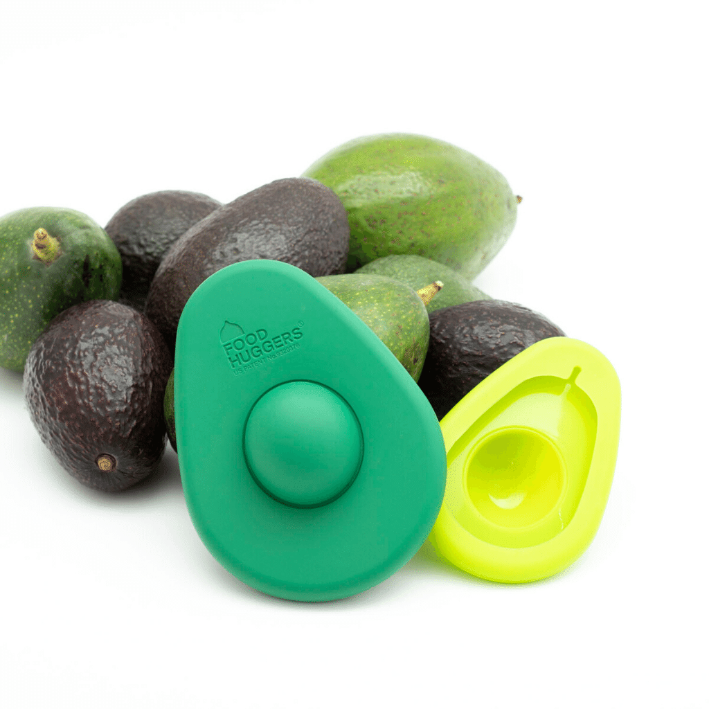 Two avocado huggers for a sustainable kitchen in front of eight avocados