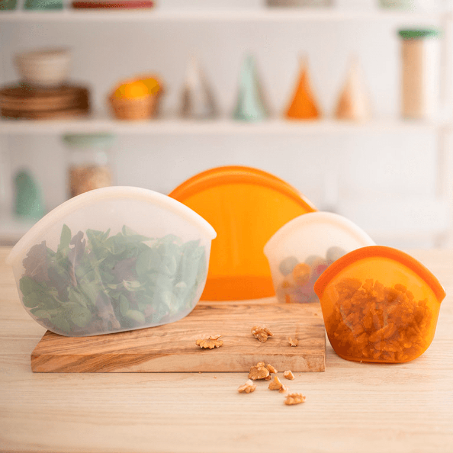 Four BPA free silicone bags on a table, three contain fruit and one is empty