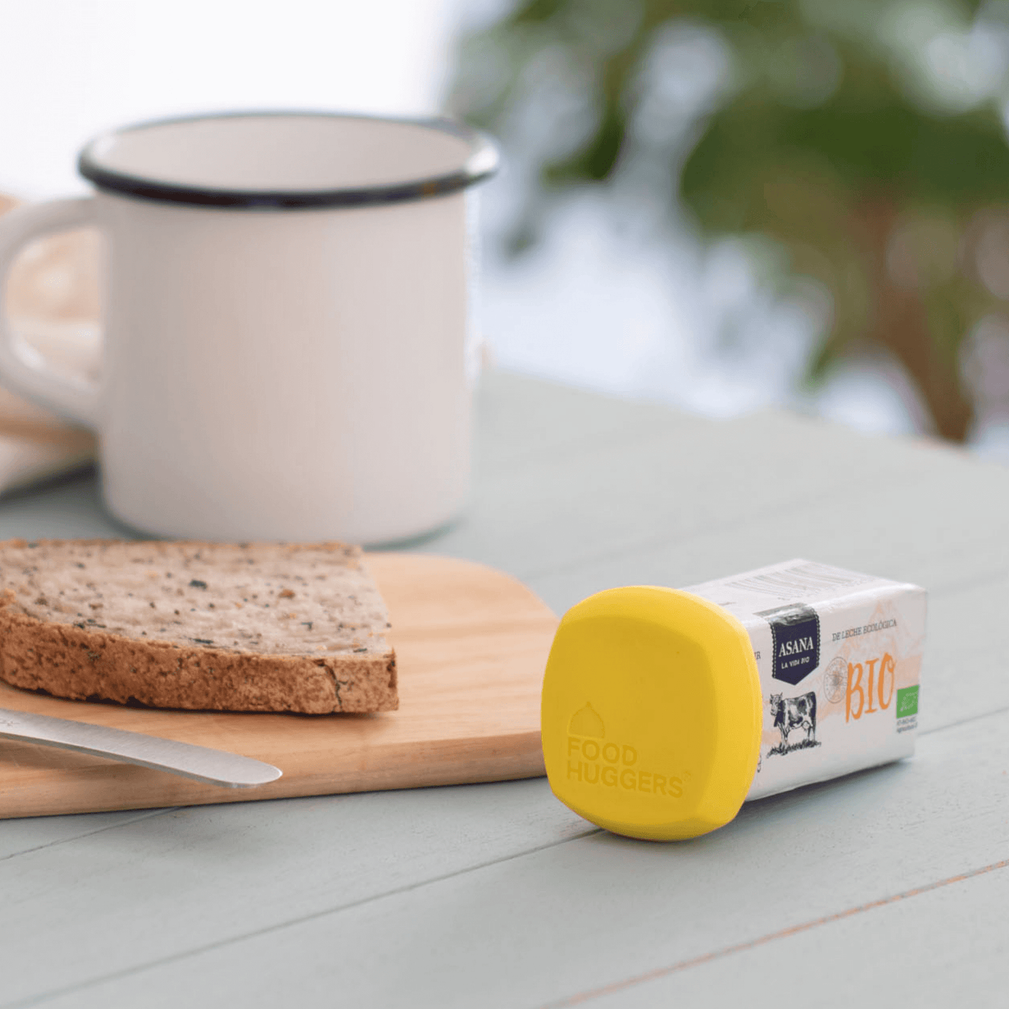 Butter Hugger preserving a stick of butter lying flat on a table next to a slice of bread