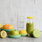 Five Food Huggers that preserve fruits for zero waste, on a gray surface next to a set of glasses