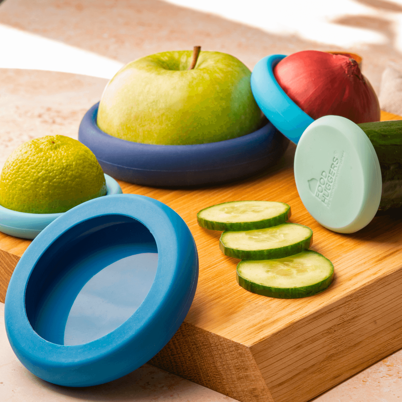 Set of five silicone Food Huggers, a sustainable alternative to plastic wrap, to protect fruits and vegetables on a wooden board