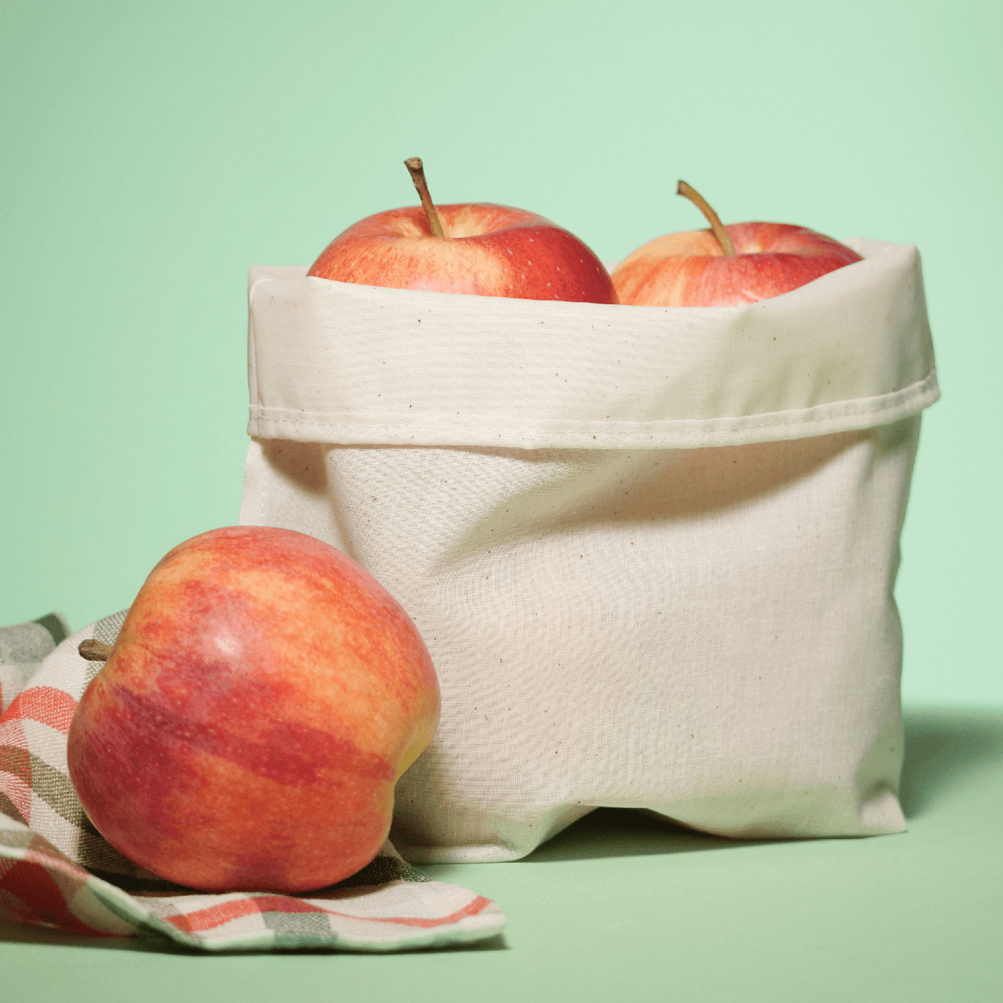 Food Huggers fabric cuff bag reusable alternative to plastic wrap preserves apples and in front of this bag an apple