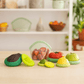 "Set of eight green silicone Food Huggers a sustainable alternative to plastic wrap to protect food on a wooden table"