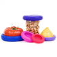 Set of five blue and pink sustainable Food Huggers that seal and preserve a tomato, and also a replacement lid for jars.