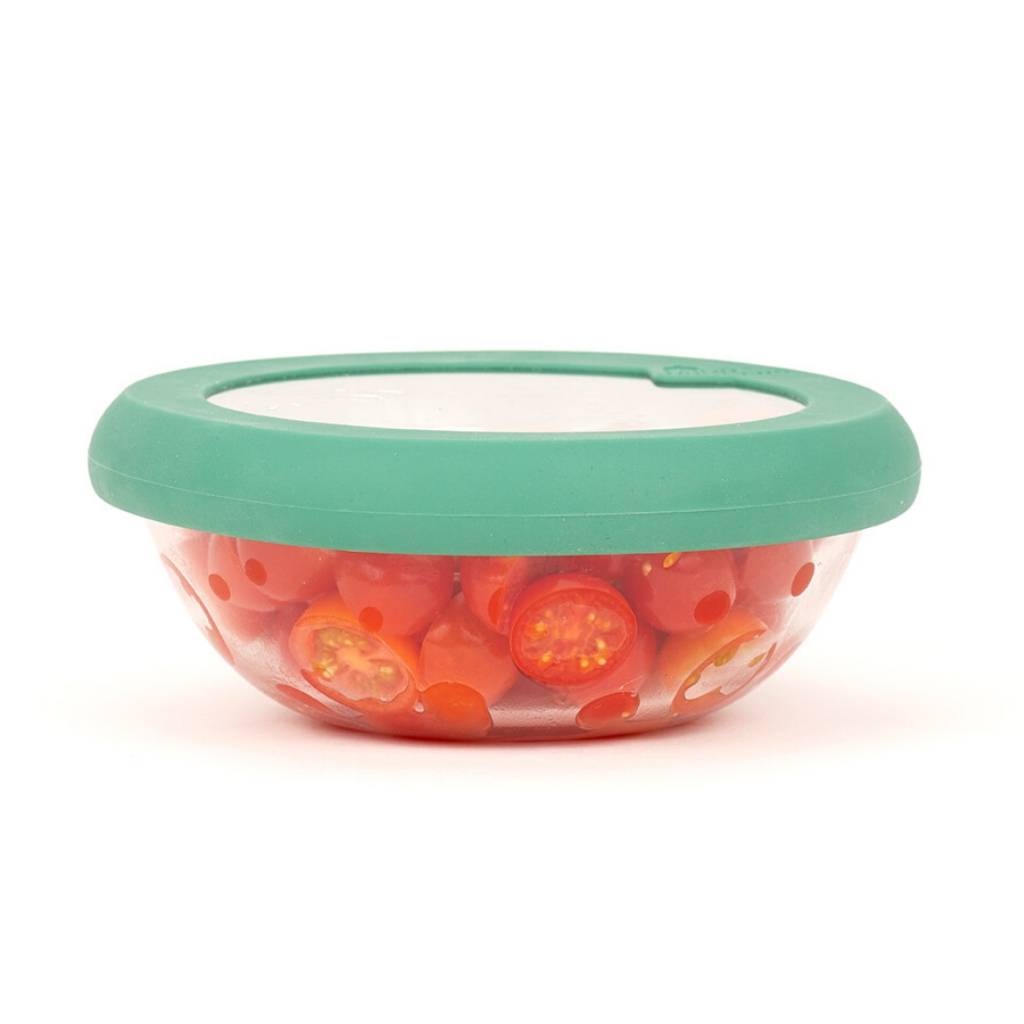 Glass bowl filled with tomatoes with green sustainable hugger lid for preserving food
